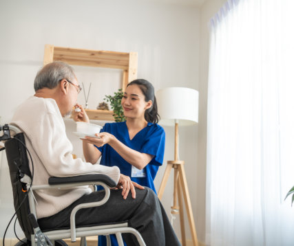 Female caregiver feed the elder man