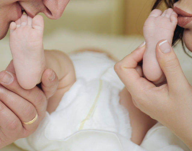 Mother and father kissing the foot of the baby