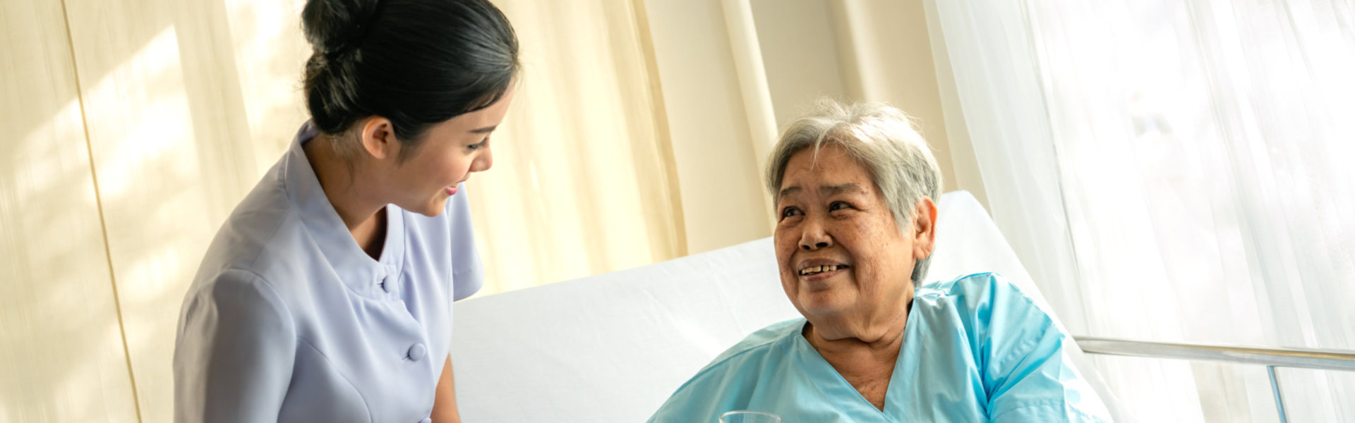 Female nurse assist the elder woman lying on bed